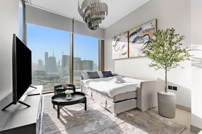 a bedroom with a bed and a tv and a potted tree at FIRST CLASS Luxury 1BR plus Bunk Room in Sobha Waves, Close to Downtown Dubai in Dubai