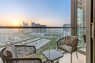 a balcony with two chairs and a view of a city at FIRST CLASS Luxury 1BR plus Bunk Room in Sobha Waves, Close to Downtown Dubai in Dubai