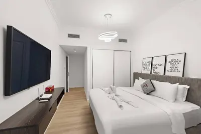 a white bedroom with a large bed and a flat screen tv at FIRST CLASS 2BR Vibrant Waterfront District in Dubai