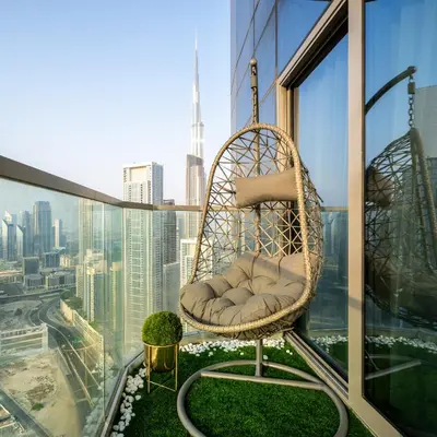 a rattan chair on a balcony with a view of the city at Sky-High Oasis with Burj Khalifa Views, Rooftop Infinity Pool, 3BR Apartment in Paramount Hotel Midtown in Dubai