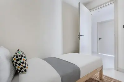 a white bedroom with a bed and a mirror at Frank Porter - Marina Vista Podium 3 in Dubai