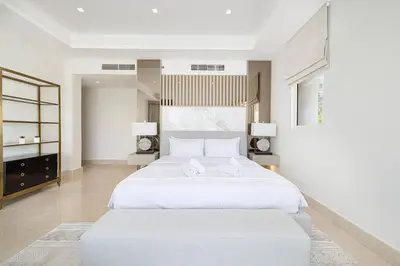 a white bedroom with a large bed and a tv at JuliusHomes - 5BR Villa with Pool in Palm Jumeirah in Dubai