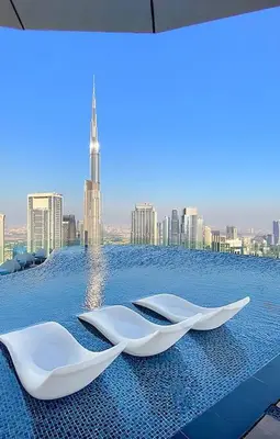 two white chairs sitting on a pool with a city skyline at FIRST CLASS 2BR Luxurious High-Floor Suite in Dubai