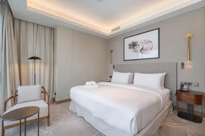 a bedroom with a large white bed and a chair at Address Residences Dubai Opera - Burj Khalifa City Views 1, 2, & 3-Bedroom Apartment 1 minute walk to Burj Khalifa, Dubai Mall, Dubai Fountain by Heaven Crest in Dubai