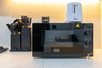 a microwave oven sitting on a counter with knives at Oraya - Upgraded 2BR In Prive Maison, Central Canal View in Dubai