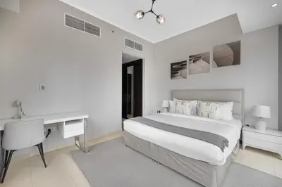 a white bedroom with a bed and a desk at Daniels 1BR at Silverene Tower Dubai Marina in Dubai