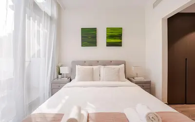 a bedroom with a large white bed with two pictures on the wall at Modern JVC 1BR with Spacious Terrace in Dubai