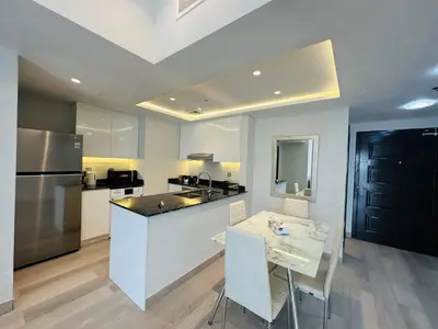 a kitchen with a counter and a table and a refrigerator at ModernLux - Brand New Modern 1BR Apartment with Lake View, JLT close to Metro in Dubai
