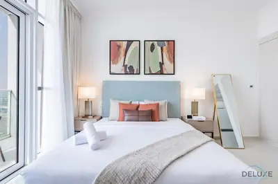 a white bedroom with a large bed with pillows at Inviting Studio in Damac Hills Carson B, Dubailand by Deluxe Holiday Homes in Dubai
