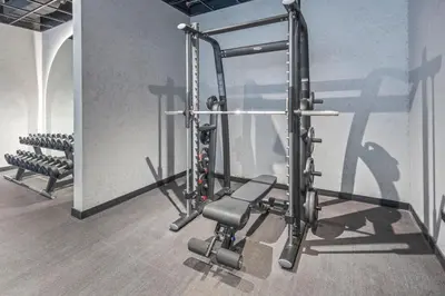 a gym with a squat rack and a bench at Premium Studio Apartment at Loci Residences JVC in Dubai