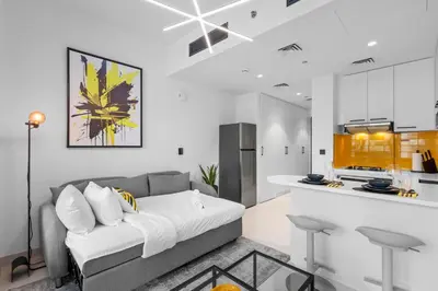 a living room with a couch and a kitchen at Premium Studio Apartment at Loci Residences JVC in Dubai