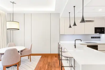 a kitchen with white cabinets and a table and chairs at Vonder Bluewaters Residences SA2 in Dubai