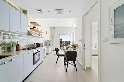 a white kitchen with a table and chairs at Chic 1 BR apartment at Golfville in Dubai