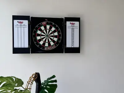 a dart board on a wall next to a plant at Chic 1 BR apartment at Golfville in Dubai