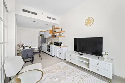 a white living room with a large tv and a table at Chic 1 BR apartment at Golfville in Dubai