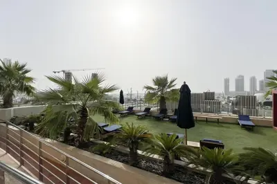 a balcony with chairs and umbrellas and palm trees at Lux 2BR with Sea Views in Marina in Dubai