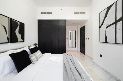 a bedroom with a white bed with black and white pillows at Brand New 1BR with Pool, Sauna & Gym in Dubai