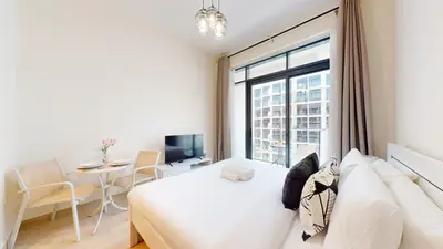 a bedroom with a bed and a desk and a window at Azizi Riviera 47 - Comfortable Studio in Meydan in Dubai
