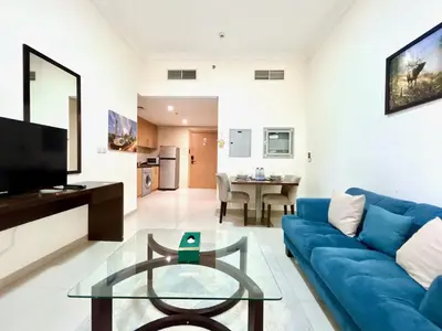 a living room with a blue couch and a glass table at Homes2Retreat - Studio in Lincoln Park Sheffield in Dubai