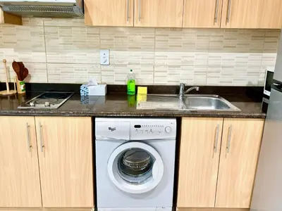 a kitchen with a washing machine and a sink at Homes2Retreat - Studio in Lincoln Park Sheffield in Dubai