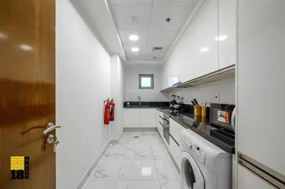 a white kitchen with a washer and dryer in it at Spacious and Peaceful 1BR with Canal views in Dubai