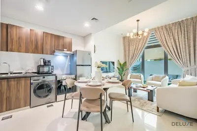 a kitchen and living room with a table and chairs at Stylish 1BR Apartment in Damac Hills 2 Avencia 45, Dubailand by Deluxe Holiday Homes in Dubai