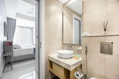 a bathroom with a sink and a mirror and a bed at Goldbest - Aykon City 2bdr in Dubai
