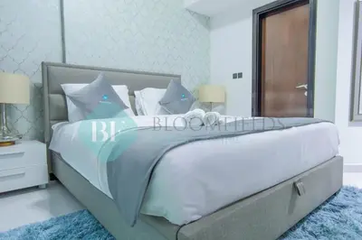 a bedroom with a large bed with white sheets and blue pillows at Bloomfields Modern 2br In Arabian Gate in Dubai