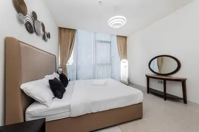a bedroom with a large bed and a mirror at Aesthetic 1Br Chrystal Lagoon in Dubai