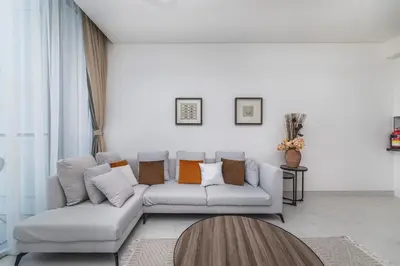 a white living room with a white couch with pillows at Aesthetic 1Br Chrystal Lagoon in Dubai