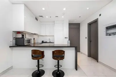 a kitchen with two bar stools and a counter at Aesthetic 1Br Chrystal Lagoon in Dubai