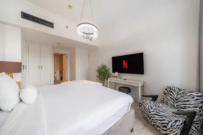 a white bedroom with a bed and a chair at Sky-High 1BR with Breathtaking Burj Khalifa View in Dubai