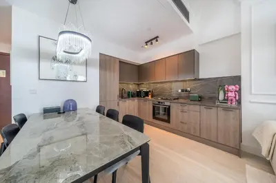 a kitchen with a large marble table with chairs at Sky-High 1BR with Breathtaking Burj Khalifa View in Dubai
