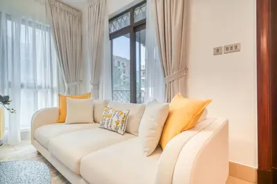 a living room with a white couch with pillows at Upscale 1-Bedroom Apt with Iconic Burj Khalifa View in Dubai