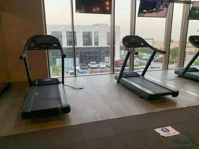 a gym with two treadmills in front of a window at Charming 3BR Townhouse with Study Room in Damac Hills 2 Centaury, Dubailand By Deluxe Holiday Homes in Dubai
