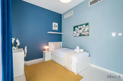 a blue room with a white bed in it at Charming 3BR Townhouse with Study Room in Damac Hills 2 Centaury, Dubailand By Deluxe Holiday Homes in Dubai