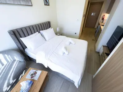 a bed with white sheets and pillows in a room at Netflix and Wi-Fi Studio Pool, Gym & City Views in Dubai