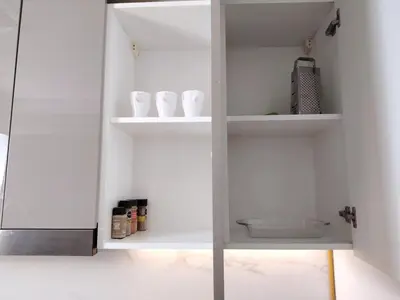 a white cabinet with white shelves in a kitchen at Netflix and Wi-Fi Studio Pool, Gym & City Views in Dubai
