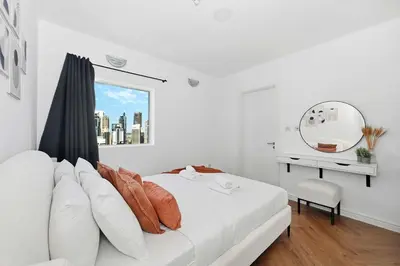 a white bedroom with a white bed and a mirror at Stunning 2 Bed Great Metro access in Dubai