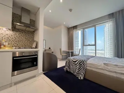 a bedroom with a bed and a kitchen with a window at In Vogue Live On the Canal in Business Bay in Dubai
