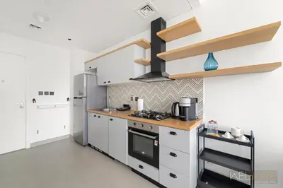 a kitchen with white cabinets and a stove at WelHome - Beautiful 1BR Apt in Dubai Hills with City View in Dubai