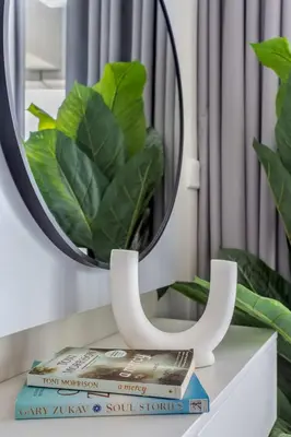 a stack of books on a table with a mirror at Frank Porter - Aykon City Tower in Dubai