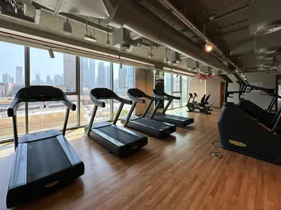 a row of treadmills in a gym with a large window at Sky High Luxury 50th FLR Lux 2BDR Apartment in Downtown in Dubai