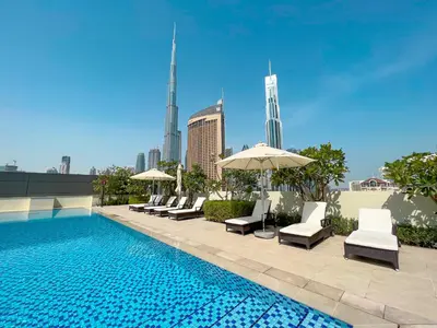 a pool with chairs and umbrellas on a building at Sky High Luxury 50th FLR Lux 2BDR Apartment in Downtown in Dubai