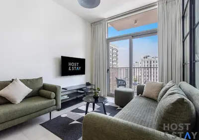 a living room with a couch and a large window at Chic Urban 2BR at Collective 2 in Dubai