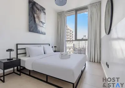 a white bedroom with a bed and a large window at Upgraded 2BR In Dubai Hills in Dubai