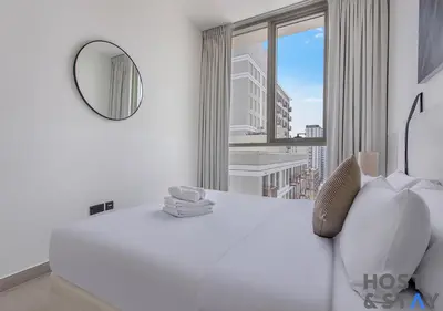 a bedroom with a white bed and a mirror at Minimalist 2BR in Dubai Hills in Dubai