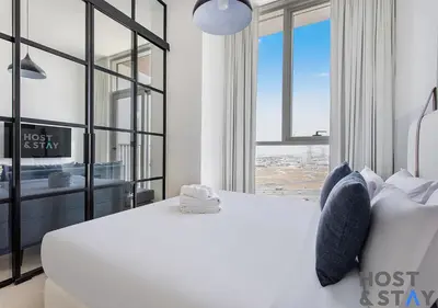 a bedroom with a white bed and a large window at Stunning 1BR in Dubai Hills in Dubai