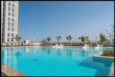 a large swimming pool with blue water in a building at Stunning 1BR in Dubai Hills in Dubai