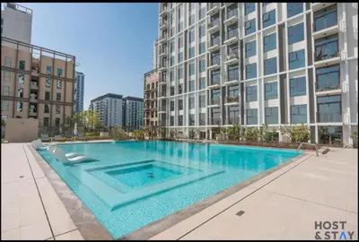 a large swimming pool in front of a tall building at Stunning 1BR in Dubai Hills in Dubai